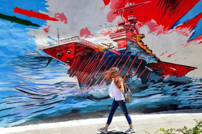 A woman walks past an anti-American and anti-Israeli mural depicting missiles hitting an aircraft carrier in Tehran, Iran, May 26, 2026. (Photo by ATTA KENARE / AFP).