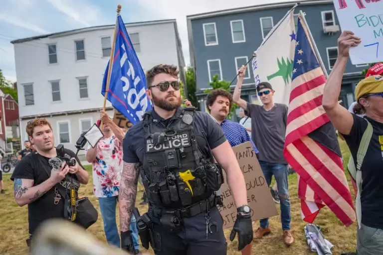 A Biddeford police officer stands guard in front of protesters during a vigil in memory of a man killed by ICE. (Ryan Murphy/Getty Images/AFP).