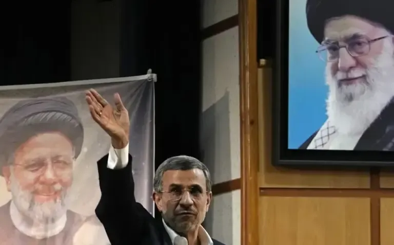 Former Iranian President Mahmoud Ahmadinejad greets the media after concluding a press conference alongside portraits of the Supreme Leader, Ayatollah Ali Khamenei, and the late President Ebrahim Raisi, on June 2, 2024. (AP Photo/Vahid Salemi).