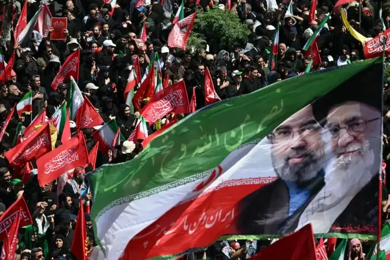 A flag with portraits of the current Supreme Leader of Iran, Mojtaba Khamenei (left), and his assassinated father, Ali Khamenei, during a funeral procession in Tehran on July 6, 2026. (Photo by Ozan KOSE / AFP).