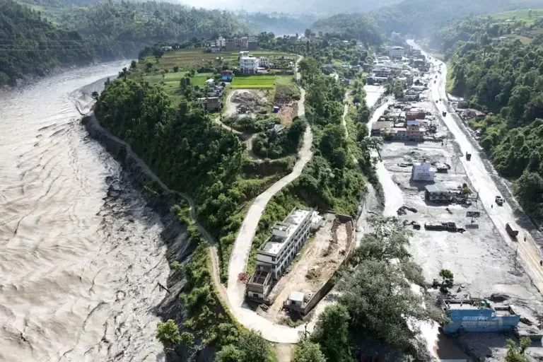 This aerial photograph shows the overflowing Trishuli River (left) and mud-covered houses (right) after the flash floods in Baireni, Dhading district, Nepal, on August 30, 2026. (Photo by Manan VATSYAYANA / AFP).