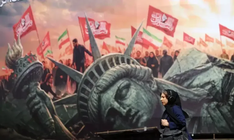 An Iranian woman walks next to an anti-American billboard in Enghelab Square, downtown Tehran, Iran, on August 13, 2026. (EFE/EPA/ABEDIN TAHERKENAREH).