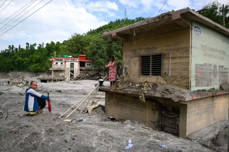 A woman is on the roof of her house, covered in mud, after the flash floods in Baireni, Dhading district, Nepal, on August 30, 2026. (Photo by Manan VATSYAYANA / AFP).
