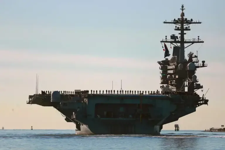 Sailors form a line on the flight deck of the USS Abraham Lincoln aircraft carrier as it departs San Diego on January 3, 2021. (KC Alfred / The San Diego Union-Tribune, via AP).