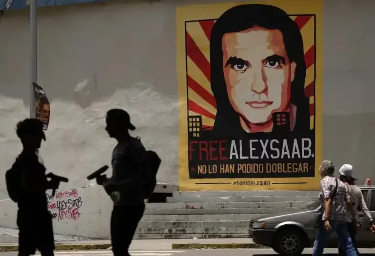 In this archive photo from September 9, 2021, pedestrians walk near an Álex Saab poster in Caracas, Venezuela. (AP Photo/Ariana Cubillos, Archive).
