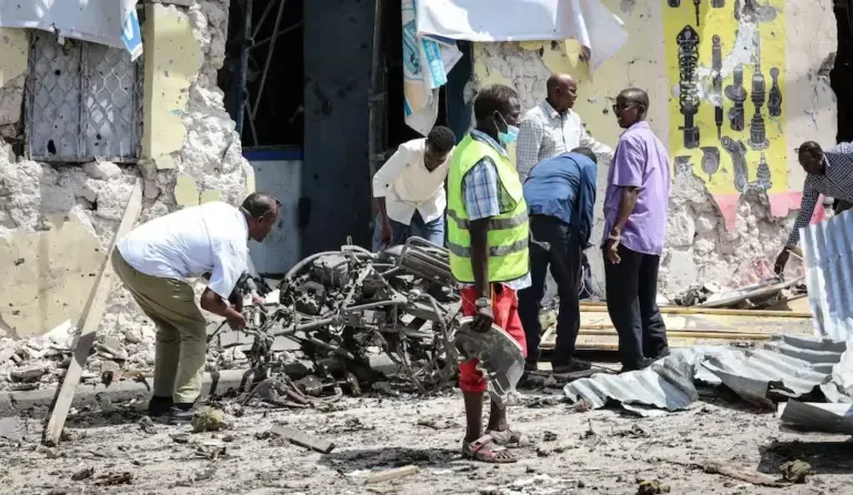 People clean debris in front of the destroyed Hayat hotel after a deadly 30-hour siege by Al Shabaab jihadists in Mogadishu on August 21, 2022. (Photo by Hassan Ali ELMI / AFP).